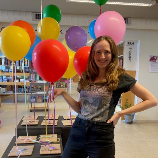 Kvinde med balloner og gaver i baggrunden
